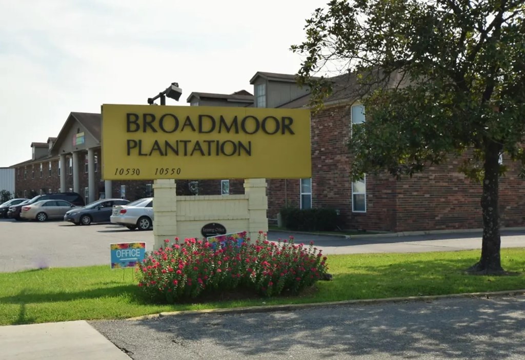 A yellow sign that says Broadmoor Plantation stands in front of a building.